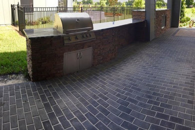 Patio kitchen - large transitional backyard brick patio kitchen idea in Orlando with a roof extension