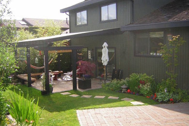 Ejemplo de patio clásico de tamaño medio en patio trasero con suelo de baldosas y pérgola