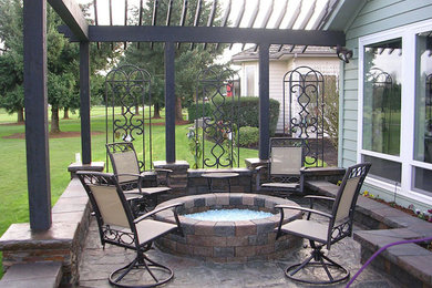Imagen de patio clásico grande en patio trasero con brasero, adoquines de ladrillo y pérgola
