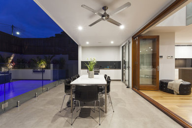 На фото: двор на заднем дворе в современном стиле с летней кухней, покрытием из бетонных плит и навесом с
