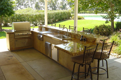 Example of a mid-sized classic backyard stamped concrete patio kitchen design in Sacramento with a roof extension