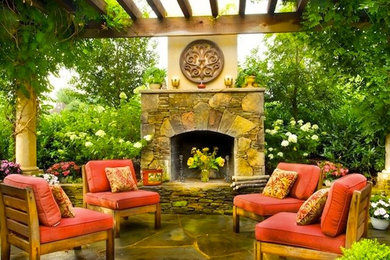 Diseño de patio mediterráneo en patio trasero con chimenea, adoquines de piedra natural y pérgola