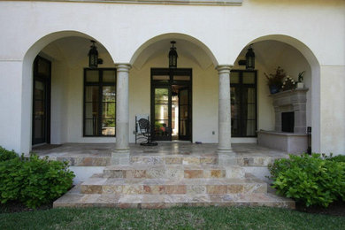 Réalisation d'une grande terrasse arrière tradition avec un foyer extérieur, des pavés en pierre naturelle et une extension de toiture.