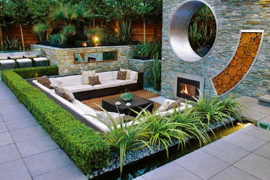 Modelo de patio contemporáneo grande sin cubierta en patio trasero con brasero y adoquines de hormigón