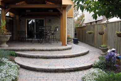 Mid-sized arts and crafts backyard concrete paver patio photo in Toronto with a pergola