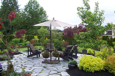 Example of a mid-sized backyard stone patio design in Vancouver