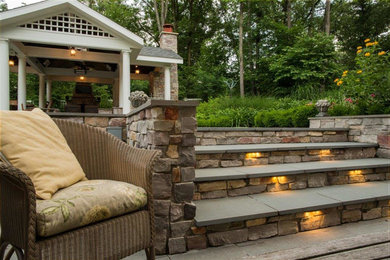 Exemple d'une terrasse arrière chic de taille moyenne avec une cuisine d'été, une pergola et des pavés en pierre naturelle.