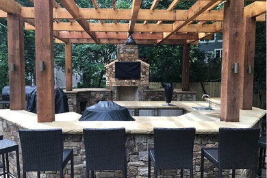 Large elegant backyard stone patio kitchen photo in Atlanta with a pergola