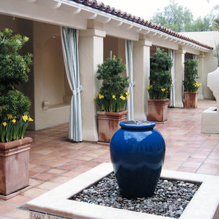 Foto di un grande patio o portico mediterraneo dietro casa con fontane, piastrelle e un tetto a sbalzo
