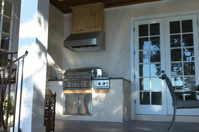 Inspiration for a mid-sized timeless backyard concrete paver patio kitchen remodel in Orlando with a roof extension