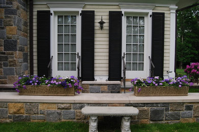 Cette image montre une terrasse arrière craftsman avec des pavés en pierre naturelle et aucune couverture.