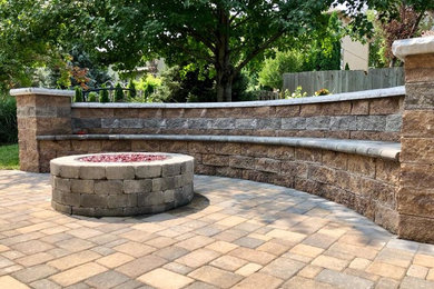Example of a mid-sized classic backyard concrete paver patio design in Omaha with a fire pit and no cover