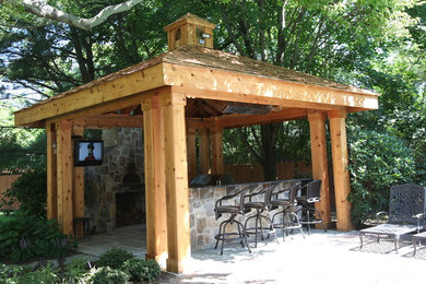 Modelo de patio de estilo americano de tamaño medio en patio trasero con cocina exterior, losas de hormigón y cenador