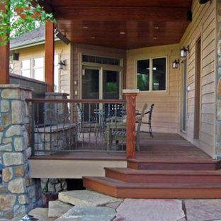Example of a mid-sized mountain style backyard stone patio design in Denver with a roof extension