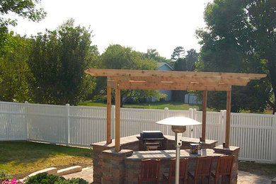 Inspiration for a large timeless backyard brick patio kitchen remodel in Other with a pergola