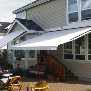 Esempio di un piccolo patio o portico classico dietro casa con pavimentazioni in mattoni e un parasole