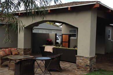 Example of a mid-sized tuscan backyard stone patio design in Los Angeles with a roof extension