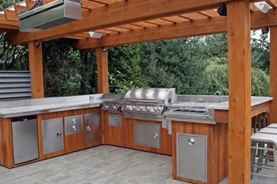 Inspiration for a large timeless backyard tile patio kitchen remodel in Orange County with a pergola