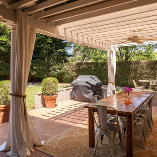 Foto di un patio o portico eclettico di medie dimensioni e dietro casa con piastrelle e una pergola