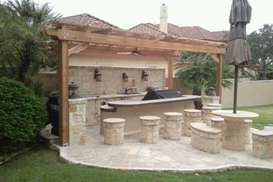 Diseño de patio mediterráneo de tamaño medio en patio trasero con cocina exterior, adoquines de piedra natural y pérgola