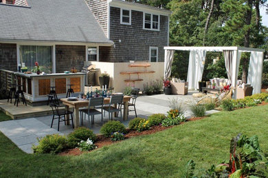 Modelo de patio clásico de tamaño medio en patio trasero con adoquines de piedra natural, cocina exterior y cenador