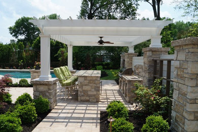 Large transitional backyard stone patio kitchen photo in St Louis with a pergola