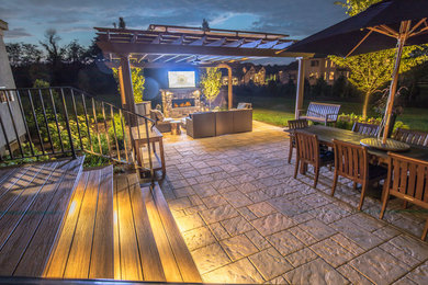 Réalisation d'une grande terrasse arrière minimaliste avec une cuisine d'été, des pavés en pierre naturelle et aucune couverture.