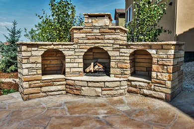 Inspiration for a large rustic backyard stone patio remodel in Denver with a fire pit