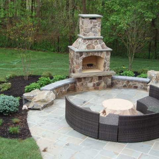 Esempio di un grande patio o portico country dietro casa con un focolare, pavimentazioni in pietra naturale e nessuna copertura