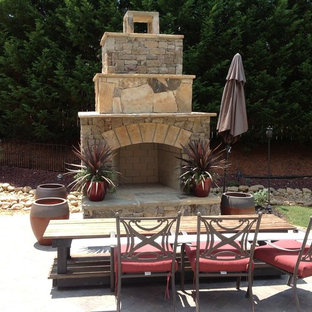 Immagine di un grande patio o portico minimal dietro casa con un focolare, pavimentazioni in pietra naturale e nessuna copertura