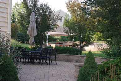 Modelo de patio actual extra grande en patio trasero con adoquines de hormigón y cenador