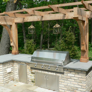 Example of a small classic backyard stone patio kitchen design in Milwaukee with a pergola