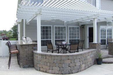 Large elegant backyard concrete patio kitchen photo in Other with a pergola