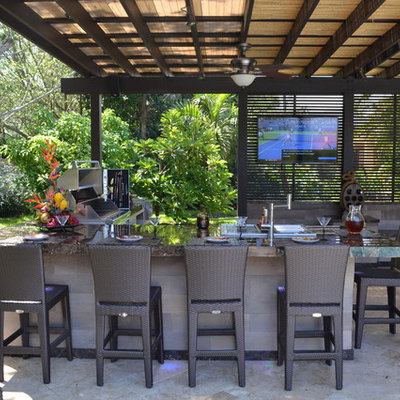 Huge elegant backyard stone patio kitchen photo in Miami with a pergola