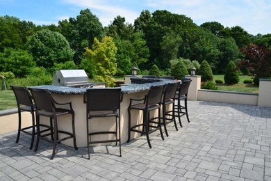 Large backyard concrete paver patio kitchen photo in Newark with no cover