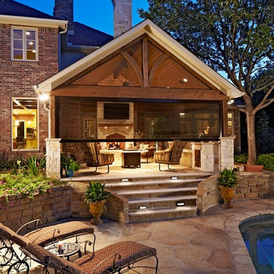 Large elegant backyard stone patio kitchen photo in Dallas with a roof extension
