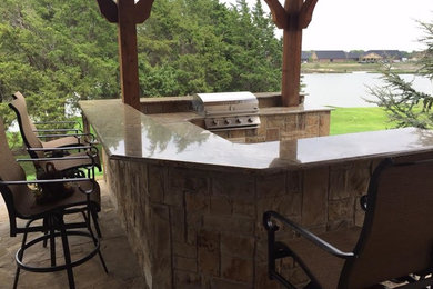 Inspiration for a mid-sized rustic backyard stone patio kitchen remodel in Dallas with a pergola
