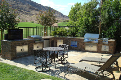 Example of a mountain style backyard stone patio kitchen design in Las Vegas