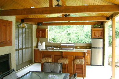 This is an example of a large traditional back patio in New Orleans with an outdoor kitchen, a roof extension and concrete slabs.