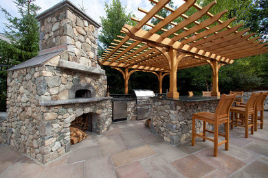 Example of a mid-sized mountain style backyard stone patio design in Boston with a fire pit and a pergola