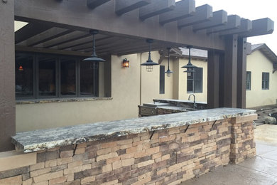Aménagement d'une très grande terrasse arrière moderne avec une cuisine d'été, des pavés en béton et une pergola.