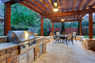 Large transitional backyard stone patio kitchen photo in Houston with a pergola