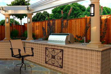 Modelo de patio clásico grande en patio trasero con cocina exterior, adoquines de piedra natural y pérgola