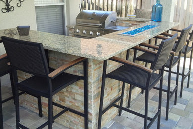 Example of a mid-sized transitional backyard concrete paver patio kitchen design in Tampa with a roof extension