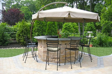 Diseño de patio minimalista en patio trasero con cocina exterior, adoquines de piedra natural y toldo