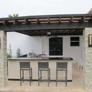 Idee per un ampio patio o portico moderno dietro casa con pavimentazioni in pietra naturale e una pergola
