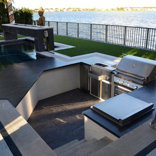 Patio kitchen - huge modern backyard stone patio kitchen idea in Miami