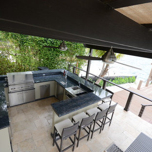 Example of a huge minimalist backyard stone patio kitchen design in Miami with a pergola