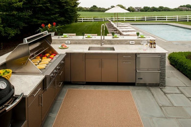Large elegant backyard concrete paver patio kitchen photo in New York with an awning