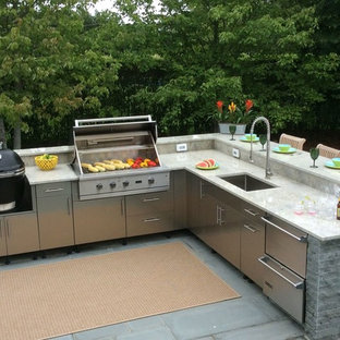 Example of a large classic backyard concrete paver patio kitchen design in New York with an awning